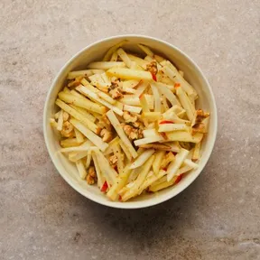 Foto van een kommetje met knolselderijsalade met appel en walnoot