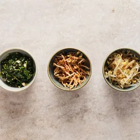 Foto van drie schaaltjes met Koreaanse bapsang: 1 met spinazie, 1 met pittige taugé en 1 met milde taugé