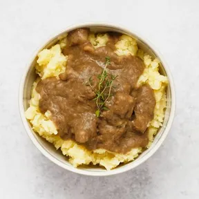Foto van een schaaltje aardappelpuree met miso-linzenjus