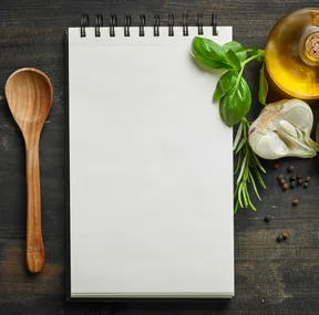 Stockfoto van een notitieblok met ingrediënten eromheen. Foto afkomstig van Adobe Stock.