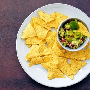 Guacamole in een kom op een bord met tortillachips