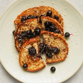 Foto van een bord met wentelteefjes met bosbessencompote en kokos