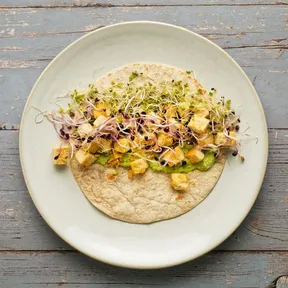 Niet opgerolde wrap met gebakken tofu, kiemgroenten en een spread van doperwtjes en mierikswortel